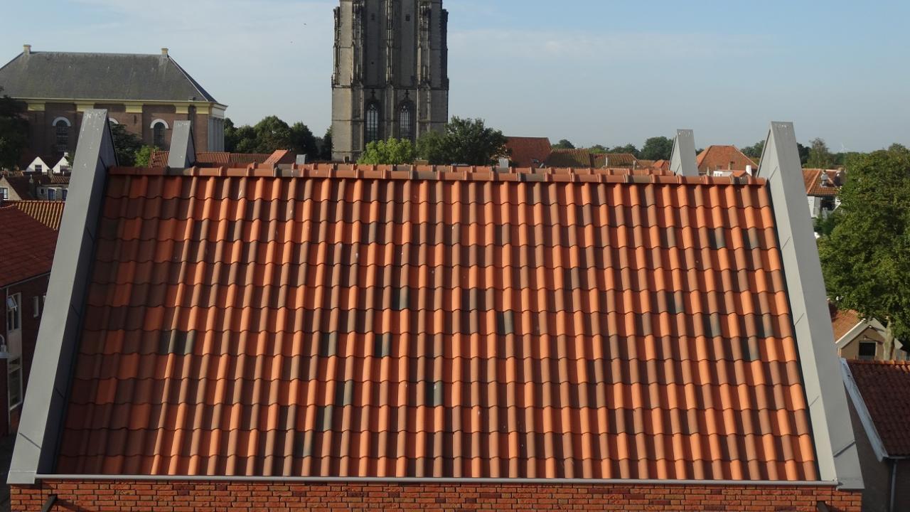 Drie kleuren dakpannen willekeurig over dak uitgestrooid