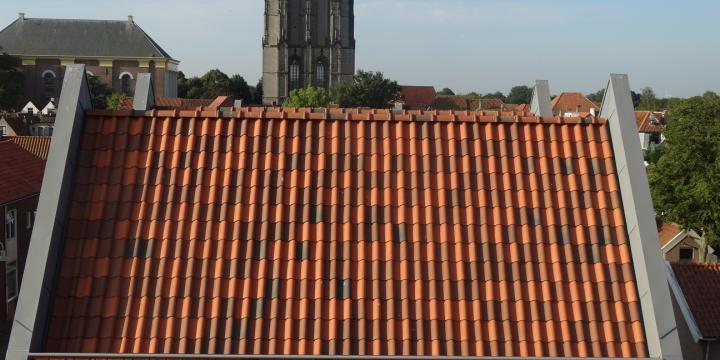 Drie kleuren dakpannen willekeurig over dak uitgestrooid